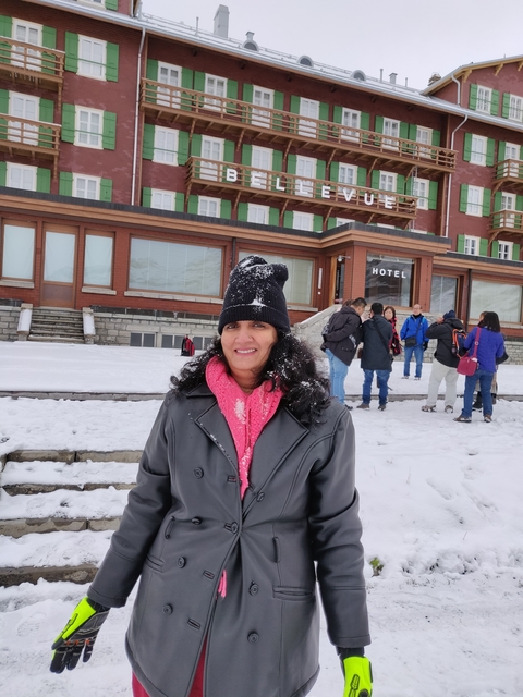 Woman smiling outside a hotel in a snowy landscape.