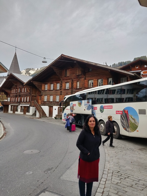 Tour bus parked in a village with alpine chalets.