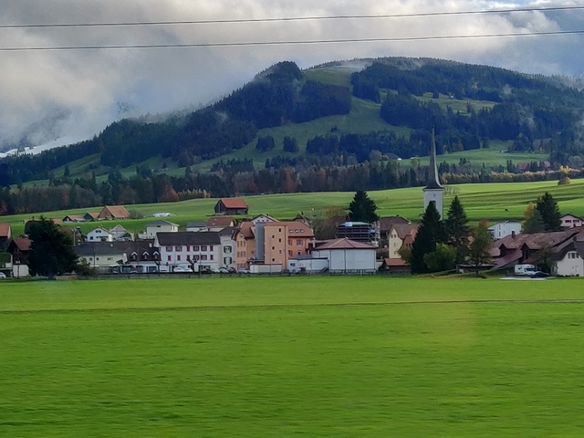 Village with houses and a church in a green valley.