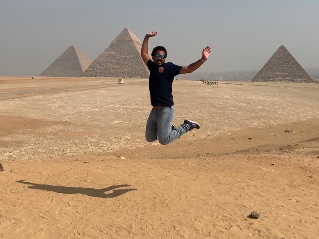 Person jumping with the pyramids of Giza in the background.