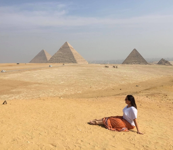 Person sitting in front of the pyramids of Giza.