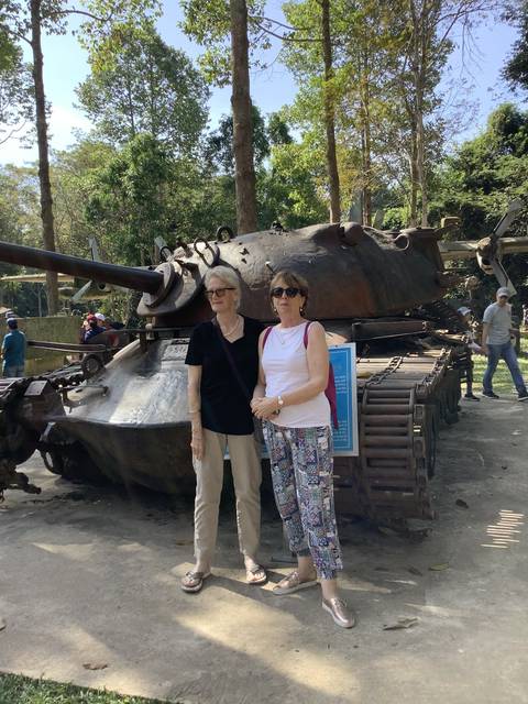 Two people posing in front of a military tank.