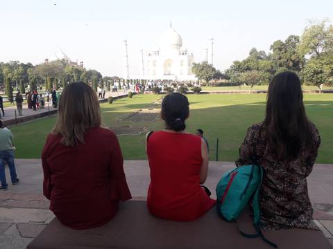 Three women sitting and looking at the Taj Mahal.