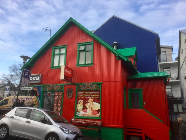A colorful building with red walls, green trim, and Coca-Cola signage.