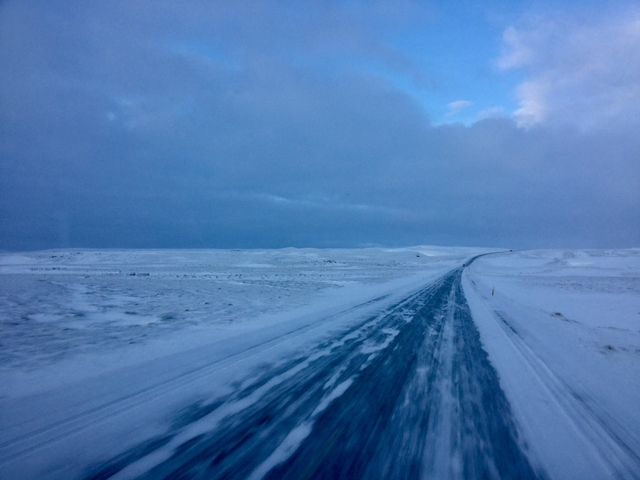 Snowy road leading into a vast, icy landscape.