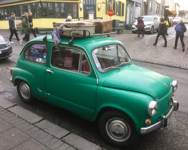 Compact vintage green car parked on a street.