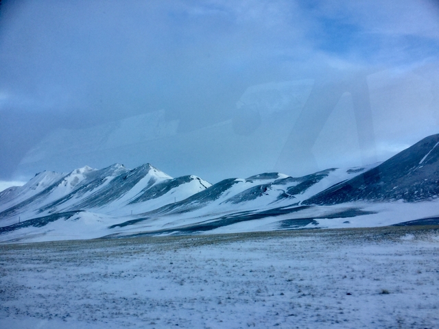 Snowy mountains under a blue sky with clouds.