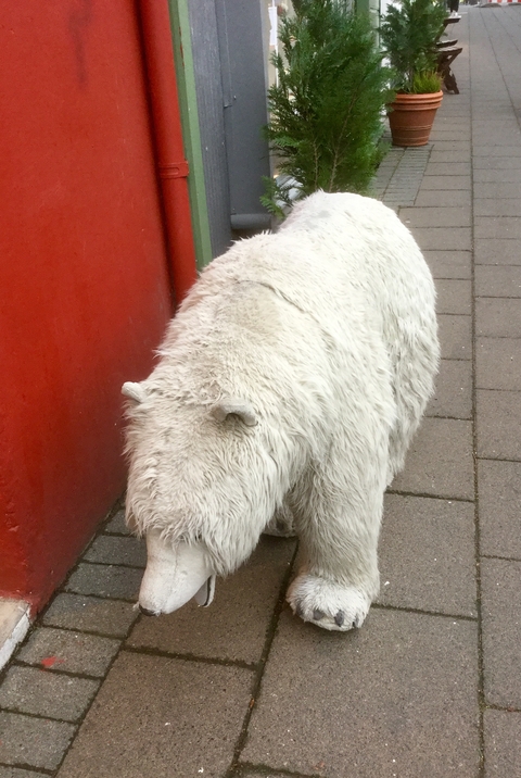 Large white bear-like sculpture against a red wall.