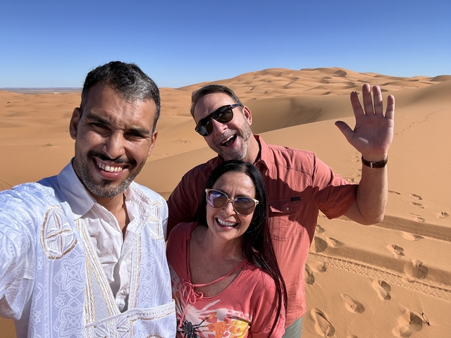 Three people posing in a desert landscape.