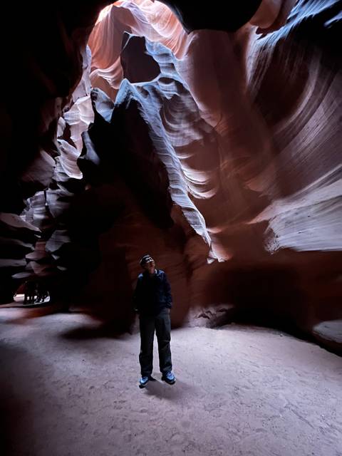 Person standing in a narrow red rock canyon.