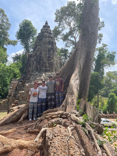 Four people in front of a temple ruin with large tree roots.