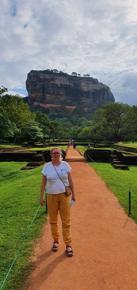 Person standing with a large rock formation in the background.