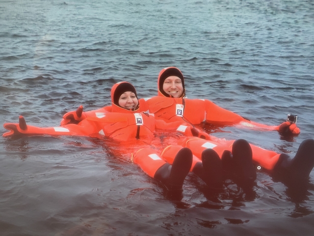 People in orange suits floating on water smiling.
