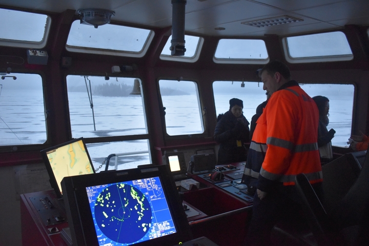 People inside a ship with nautical instruments and maps visible.