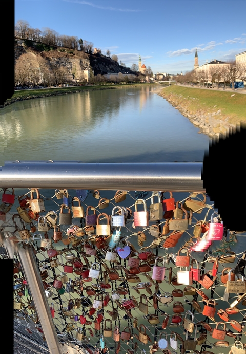 Locks attached to a bridge railing over a river.