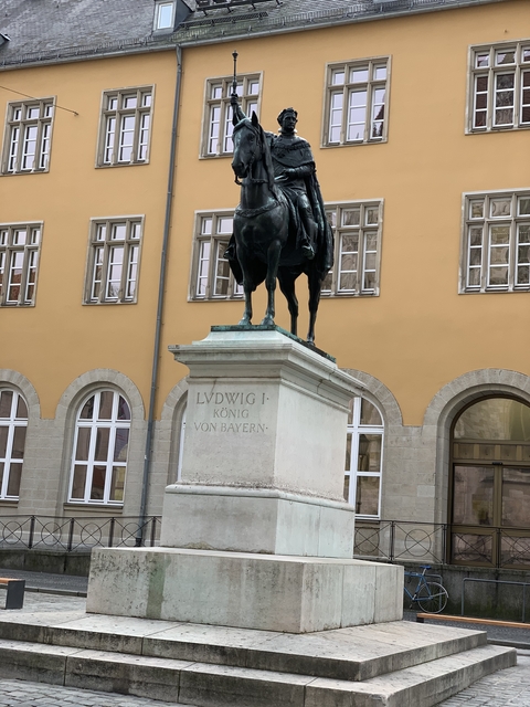 Statue of Ludwig I on a pedestal in front of a classical building.