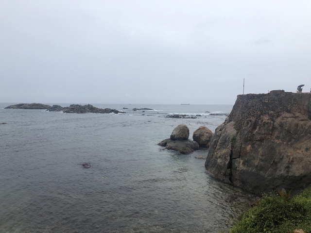 Rocky coastline with ocean waves under a cloudy sky.