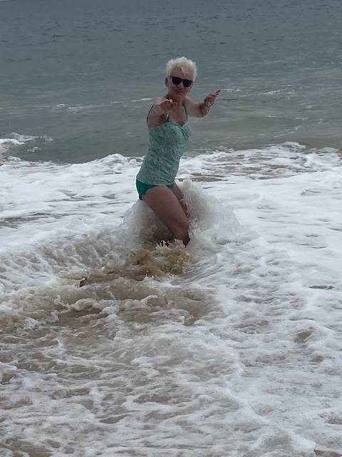 Individual playing in ocean waves wearing sunglasses.