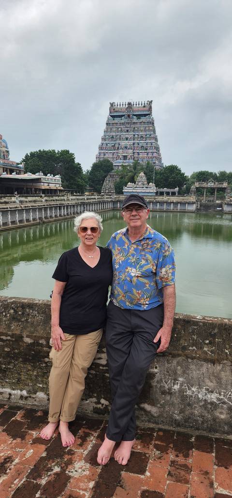 Couple posing in front of a temple with water.