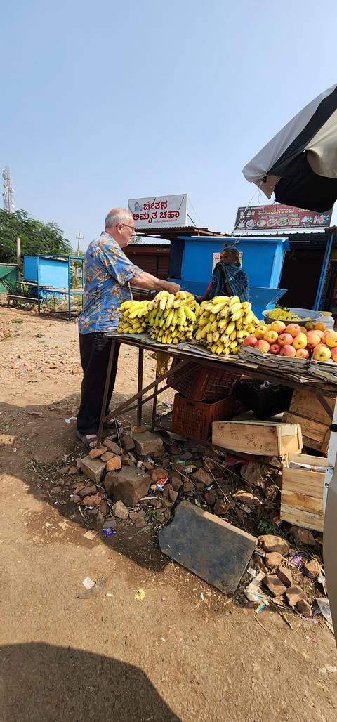 Man buying fruits at an outdoor market stall.