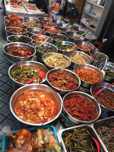 Variety of Korean side dishes and kimchi in metal bowls.