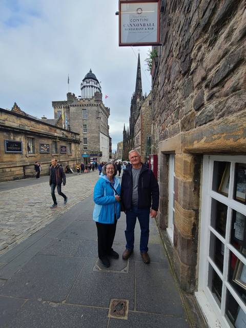 Two people standing on a cobblestone street with historical architecture.
