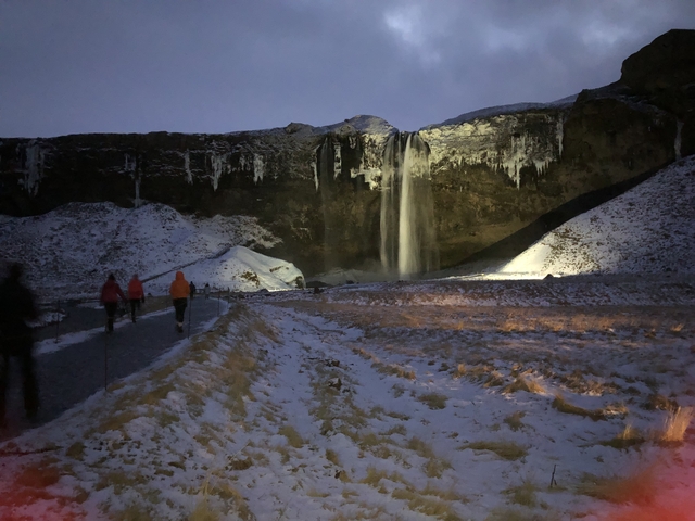 A waterfall surrounded by a snowy landscape at twilight.