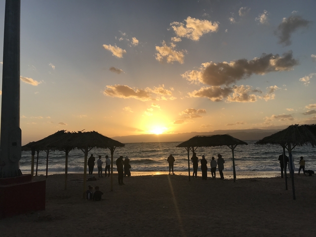 Silhouettes of people on a beach watching a beautiful sunset.