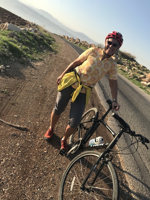 Cyclist standing on a slanted road.