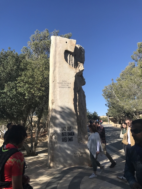 Monument with engraved text surrounded by people.