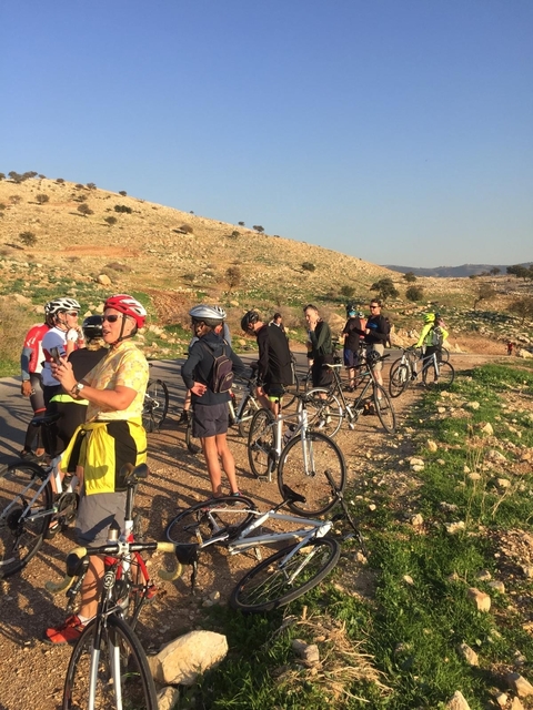 Cyclists gathered on a rural road in a hilly area.