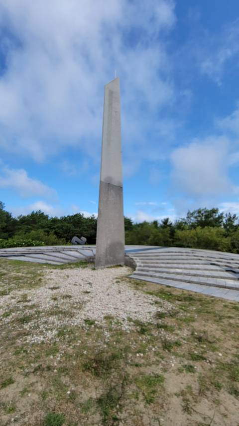 An obelisk surrounded by circular steps under a blue sky.