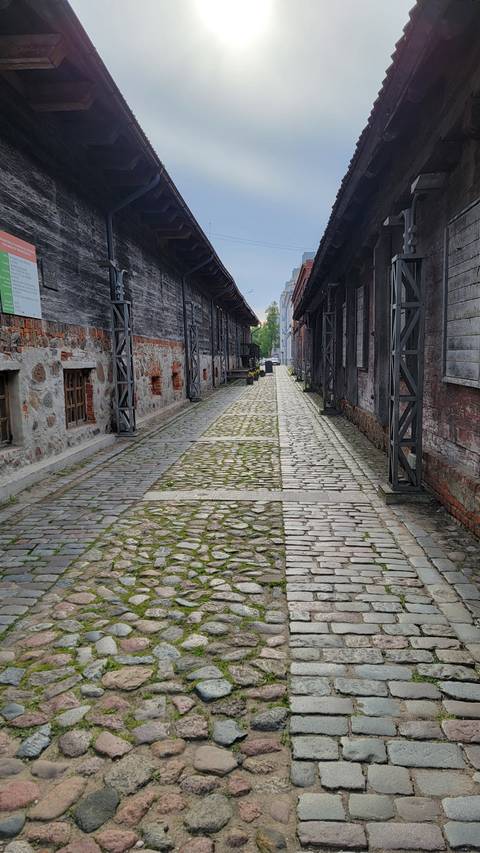 Narrow cobbled path between wooden buildings.