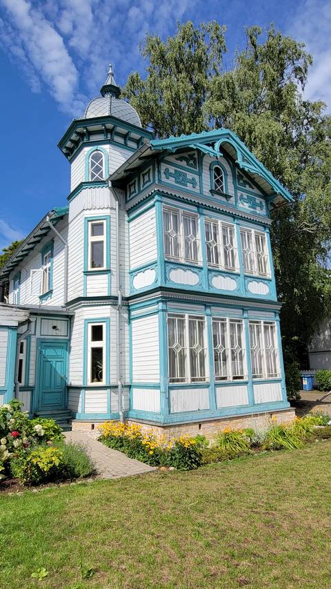 A beautifully detailed wooden house under a bright sky.