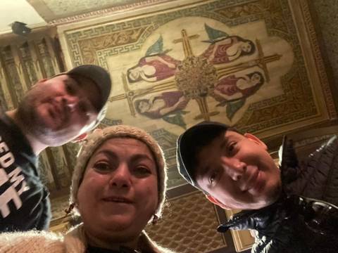 Three people taking a photo with a decorated ceiling above.