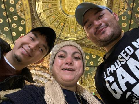 Three people posing under a detailed ceiling.