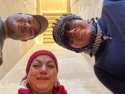 Three people with a stone wall in the background.