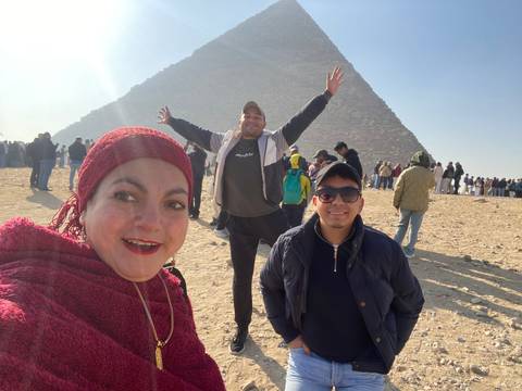 Three people posing with a pyramid.