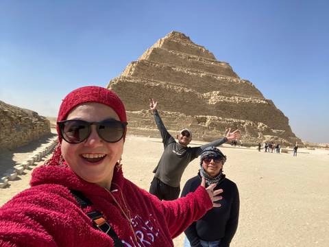 Three people posing with a stepped pyramid.