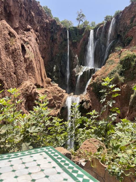 Waterfall cascading down the cliff with a tiled table in the foreground.