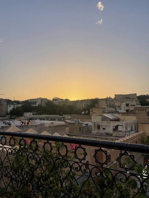 Sunset view over a city with wrought iron balcony railing.