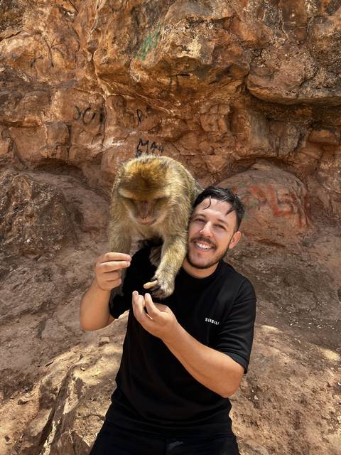 A person smiling with a Barbary macaque.