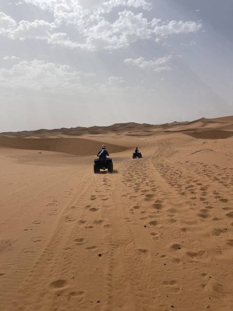 People riding quad bikes on sand dunes.