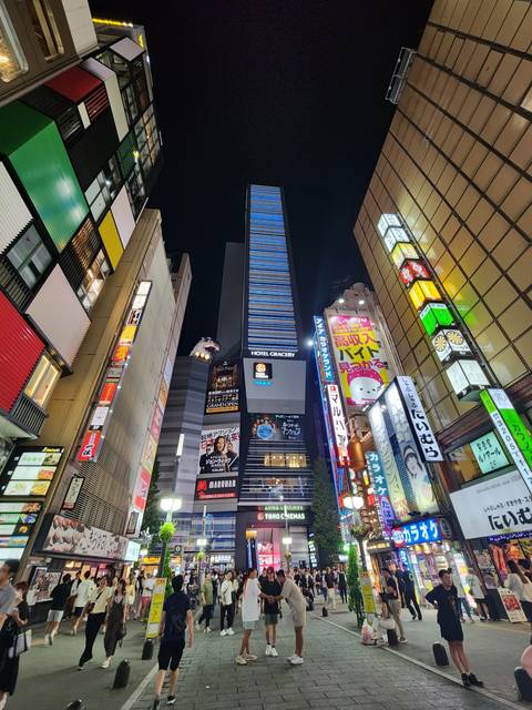 Busy urban street scene with colorful billboards at night.