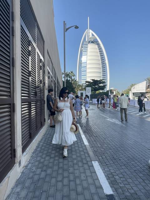 Burj Al Arab with tourists on a paved walkway.