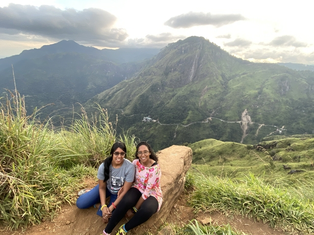 Two people sitting on a mountain with a scenic valley view.