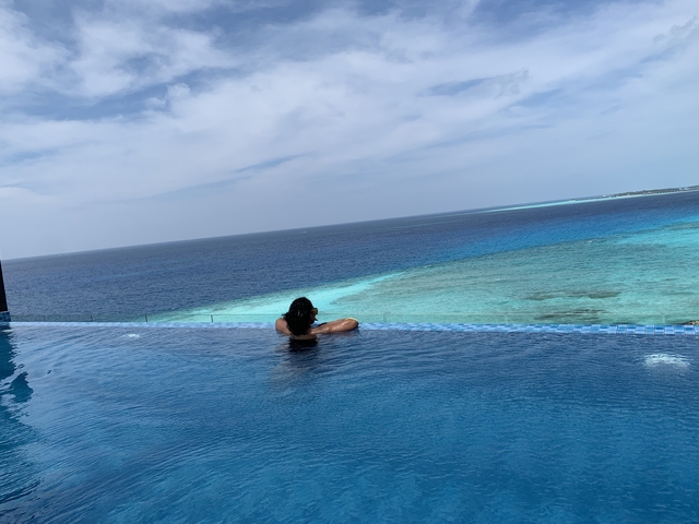 Person relaxing on the edge of an infinity pool overlooking the ocean.