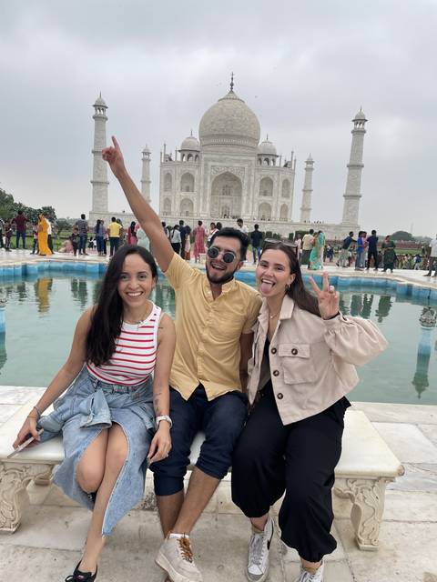 Three people posing in front of the Taj Mahal.