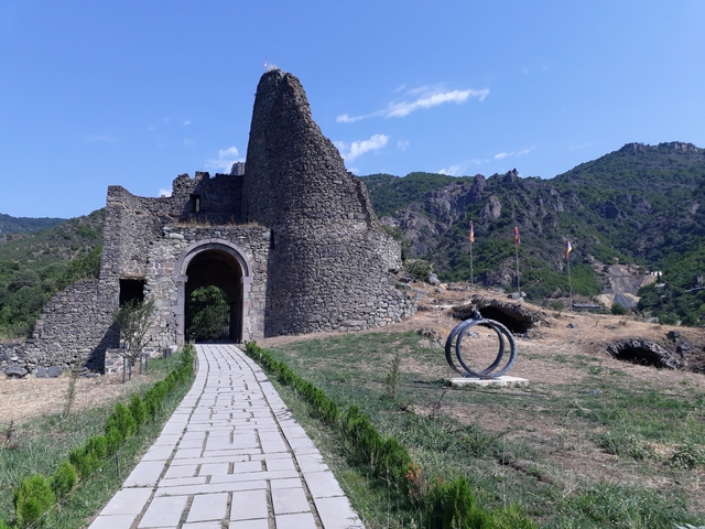 Ruins of a stone structure surrounded by rocky hills.