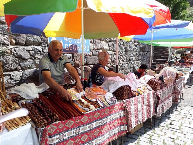 Market stall with fruits and traditional goods under colorful umbrellas.